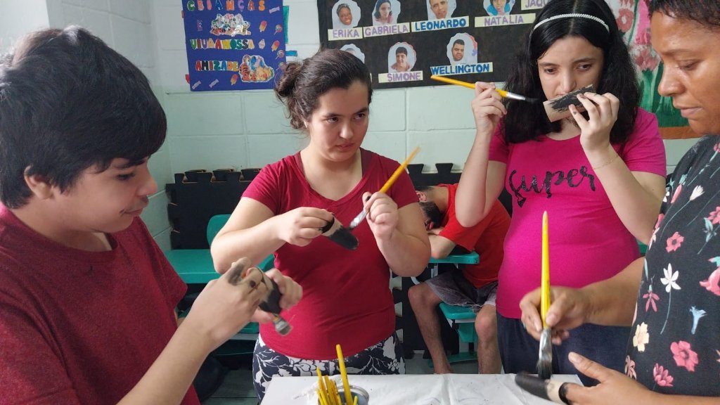 Participantes da AMME em oficina de artesanato, manuseando materiais coloridos