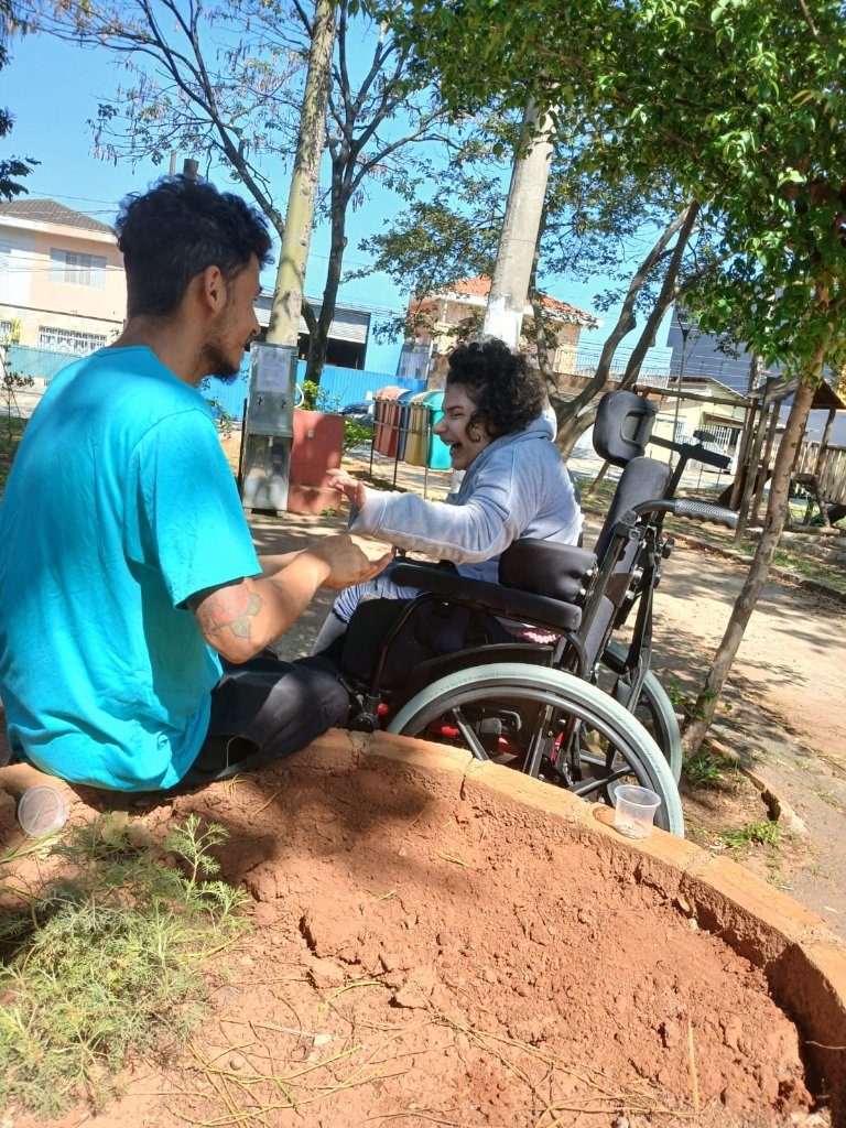 Atividade na horta terapêutica ao ar livre, com profissional e pessoa em cadeira de rodas